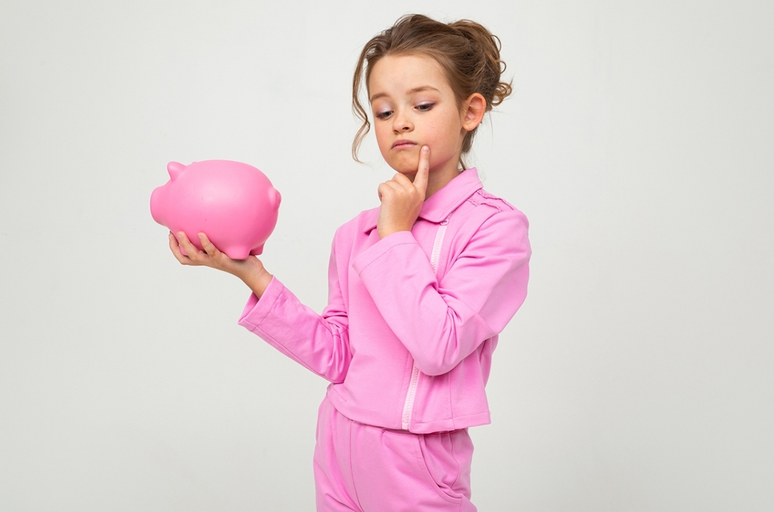 Child thinking holding piggybank